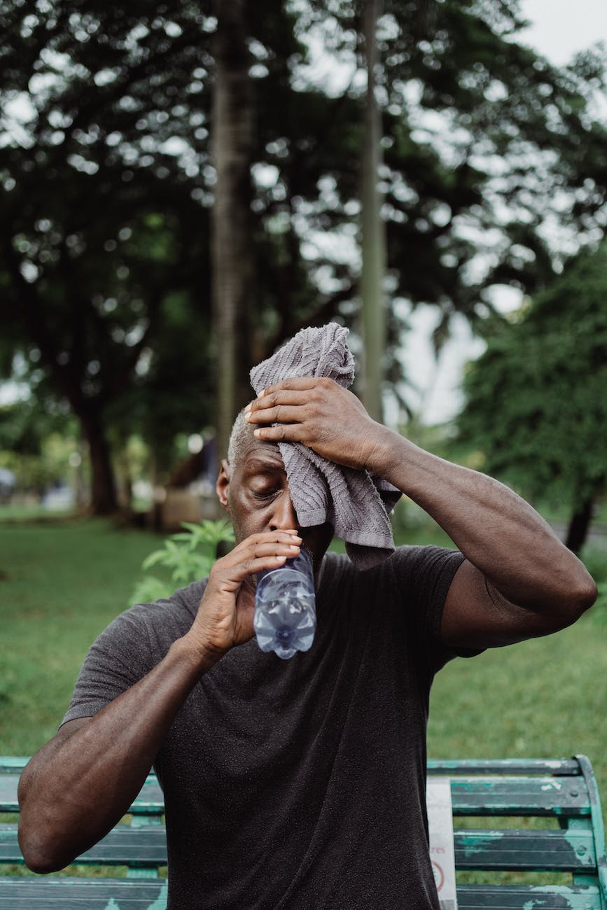 man in black shirt drinking water from plastic bottle